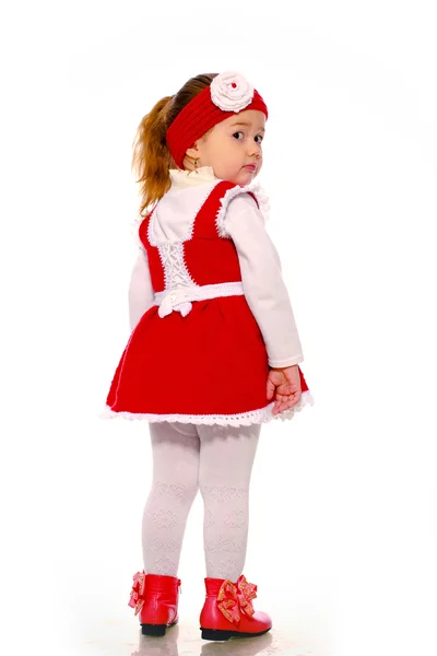 Ein kleines Mädchen in einem Strickkleid auf weißem Hintergrund — Stockfoto