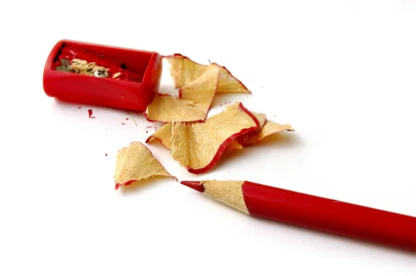 Lápis vermelho e resíduos de madeira sobre fundo branco — Fotografia de Stock