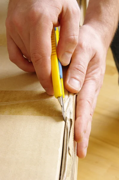 stock image Men unpacking box with cutter