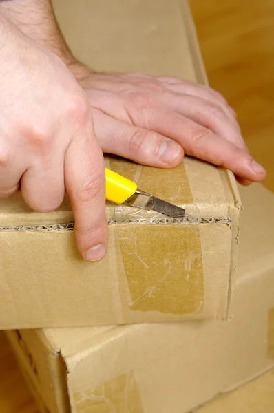 Man unpacking box with cutter — Stock Photo, Image