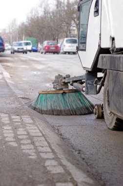 A sweeping machine cleans the street clipart