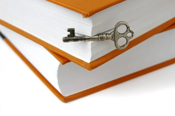 Boeken en sleutel geïsoleerd op wit — Stockfoto