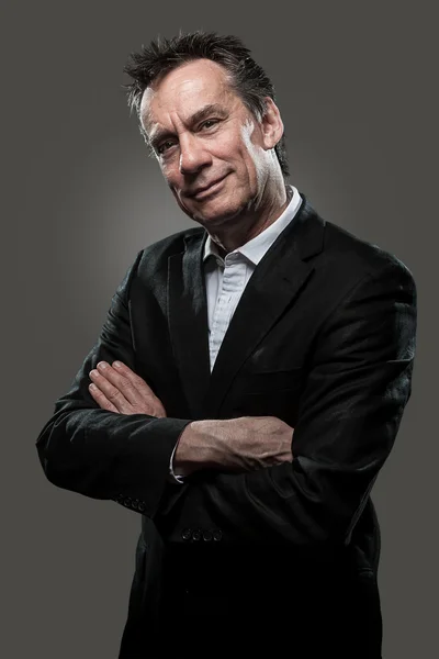 Hombre de negocios sonriente brazos doblado gris fondo alto contraste — Foto de Stock