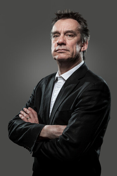 Stern Imposing Business Man with Arms Folded on Grey Background