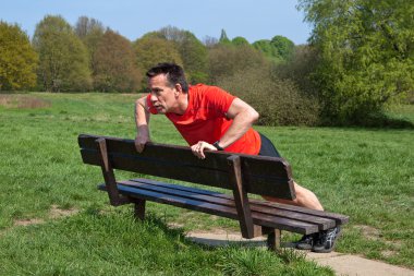 adam pressups güneşin bir parkta bankta yaparken egzersiz