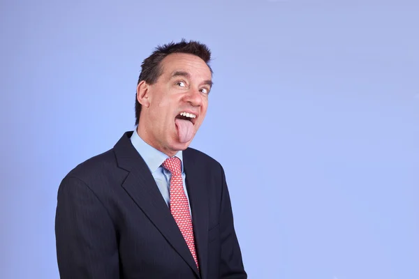 Business man in pak uitsteekt tong op blauwe achtergrond — Stockfoto