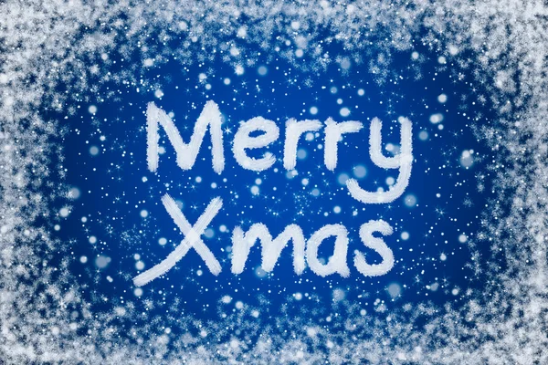 Vánoční modré pozadí s merry xmas textem v sněhu psaní — Stock fotografie