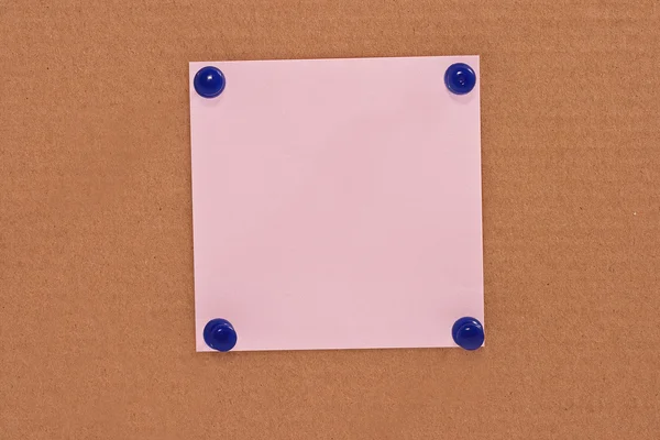 Рожевий папір для нотаток, прикріплений блакитними шпильками — стокове фото