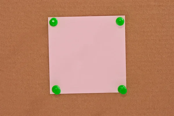 Рожевий папір для нотаток, прикріплений зеленим штифтом — стокове фото
