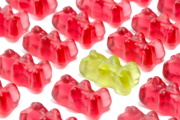 Green gummy bear among red — Stock Photo, Image