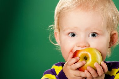 Child with an apple on a green background clipart