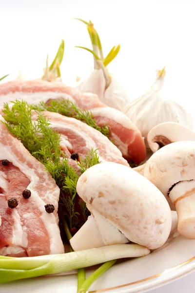 Rauw vlees met paddestoelen, specerijen en kruiden op een plaat — Stockfoto