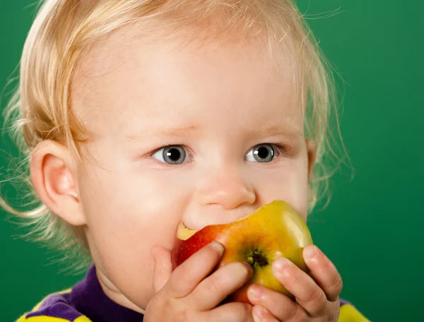 Stock image A child with an apple on a green background