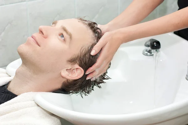 Loira em um salão de estar lavado seu cabelo com sha — Fotografia de Stock