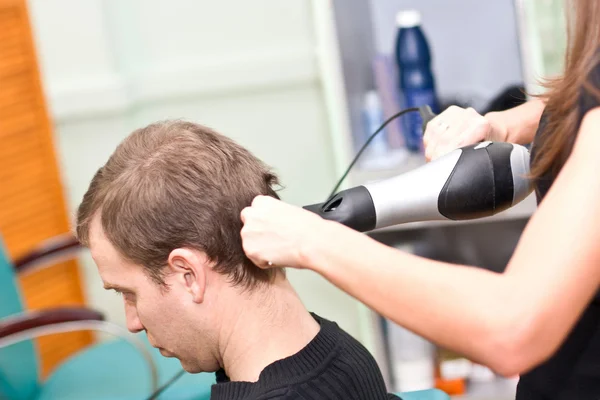 Парикмахер сушит волосы парню — стоковое фото