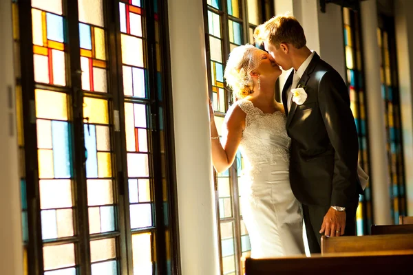 Bride and Groom kissing in front of stained glass — Stock Photo, Image