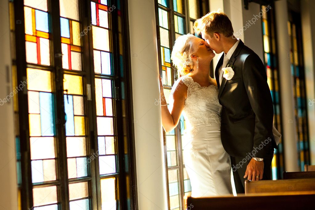 Bride and Groom kissing in front of stained glass