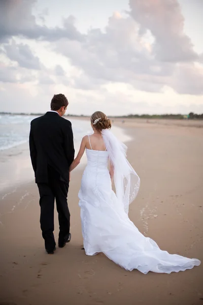新娘和新郎，手牵手走在沙滩上 — 图库照片