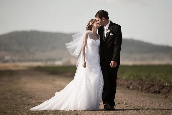 Noiva e noivo andando por uma estrada rural — Fotografia de Stock