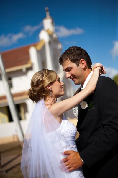 Närbild på bruden och brudgummen kramas, kyrkliga bakom — Stockfoto