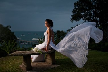 Bride sitting with dress blowing in the wind clipart