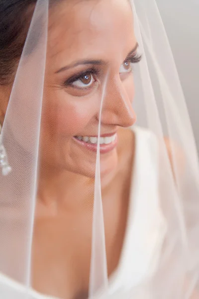 美しい花嫁彼女のベールを通して見ると笑みを浮かべて — ストック写真