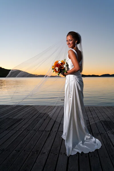 Noiva recém-casada ao pôr do sol com véu estendido — Fotografia de Stock