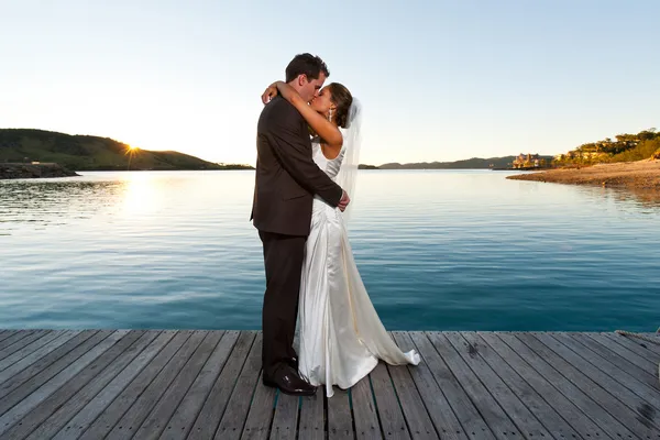 일몰에는 부두에 키스 하는 신혼 부부 스톡 사진