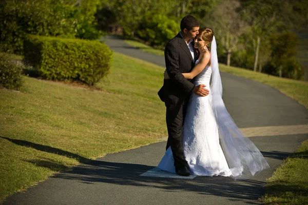 Newlyweds embracing on a winding path — Stock Photo, Image