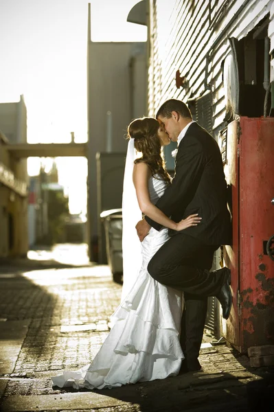 Recém-casados se beijando apaixonadamente contra uma caixa vermelha — Fotografia de Stock