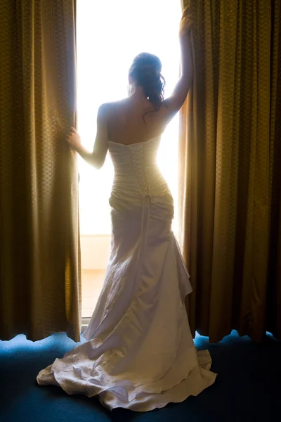 Mariée par derrière regardant à travers les rideaux — Photo