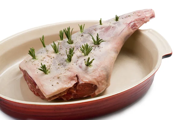 Perna crua de cordeiro com alecrim em um prato assado — Fotografia de Stock