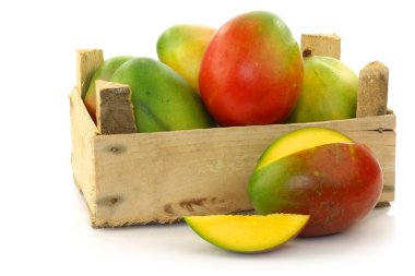 Fresh mango fruit and a cut one in a wooden box clipart