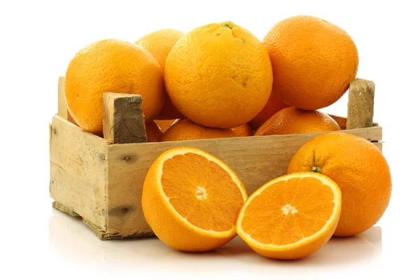 Naranjas frescas y dos mitades en una caja de madera —  Fotos de Stock