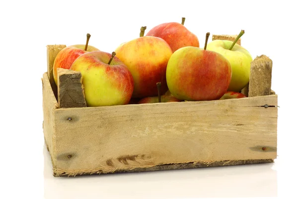 Fresh red and yellow apples coming from a wooden box — Stock Photo, Image