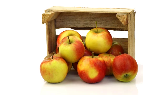 Fresh red and yellow apples coming from a wooden box — Stockfoto