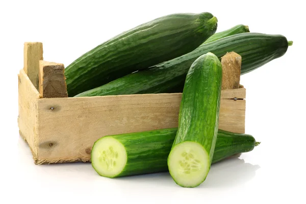 Fresh cucumbers and a cut one in a wooden box — Stock Photo, Image