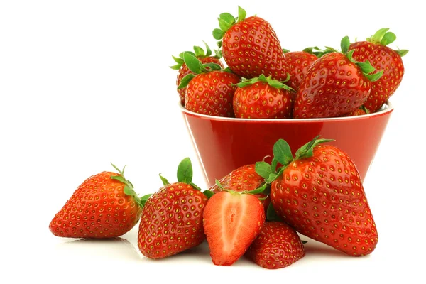 Red bowl full of fresh strawberries and a cut one — Stock Photo, Image
