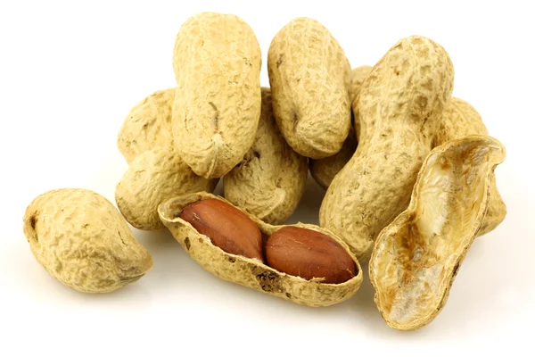 stock image A bunch of fresh roasted peanuts and a peeled one