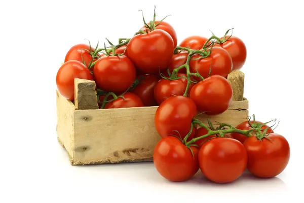 Frische Tomaten am Weinstock in einer Holzkiste — Stockfoto