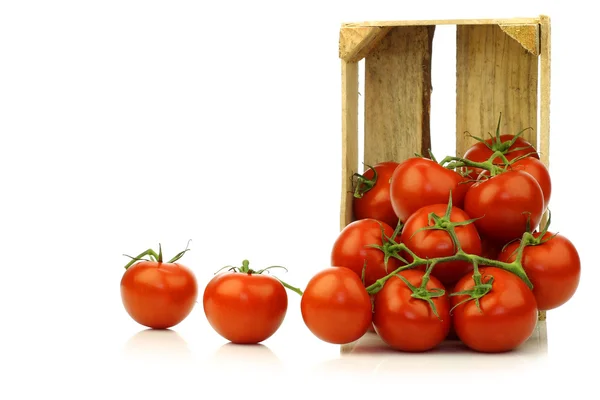 Свежие помидоры на виноградной лозе в деревянном ящике — стоковое фото