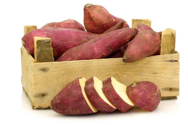 Bos van zoete aardappelen en een verlaging van één in een houten krat — Stockfoto