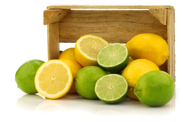 Fresh lemons and lime fruits and some cut ones in a wooden box — Stock Photo, Image