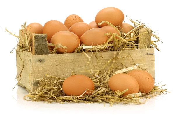 Bunch of fresh brown eggs and some straw in a wooden crate — Stock Photo, Image