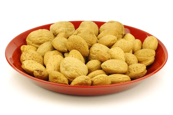 Assorted nuts on a red dinner plate — Stock Photo, Image