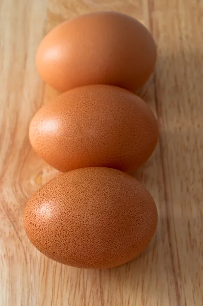 Three eggs on top the chopping board. — Stock Photo, Image