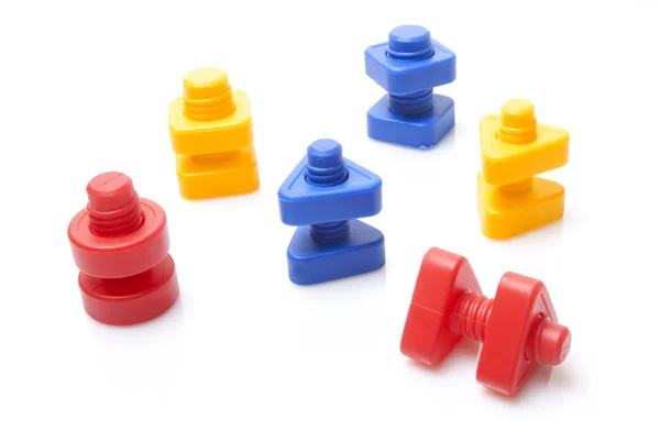 Tornillos y tuercas de juguete de colores sobre fondo blanco — Foto de Stock