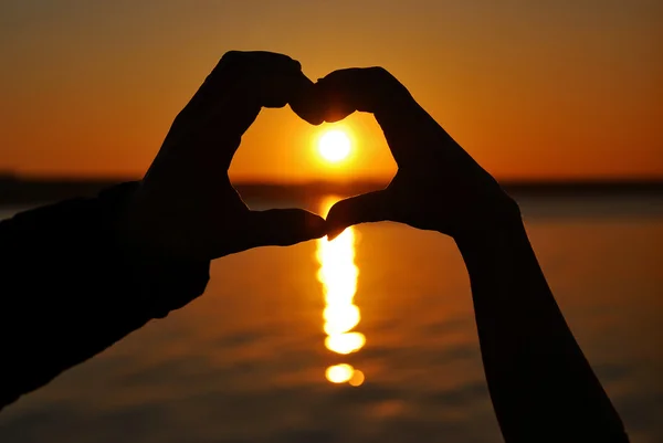 Flicka och pojke göra ett hjärta vid solnedgången — Stockfoto