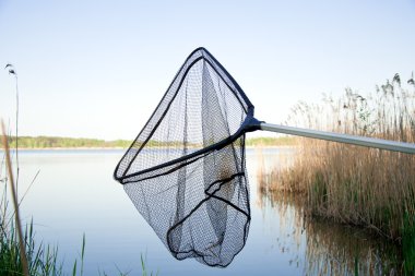 Landing net on the lake outside clipart