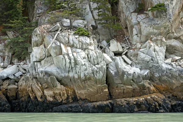 Le rocce creano un muro di pietra in bellissimi colori sul bordo dell'acqua — Foto Stock